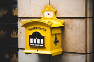alter, gelber Briefkasten an einer Hauswand