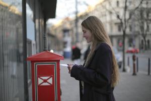 Frau mit Brief an einem Briefkasten