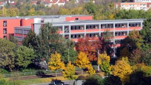 Blick auf die GS "Saaletalschule" mit Straßenbahnschienen und Bäumen