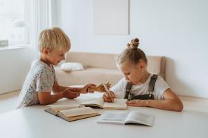 Junge und Mädchen sitzen an einem Tisch beim Lernen