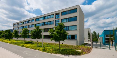 Blick auf das "Otto-Schott-Gymnasium" mit Grünanlage und Schulhof